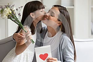 Little daughter congratulate excited young mom presenting flowers photo