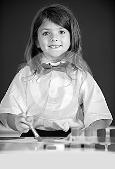 Cute little girl child painting with paints color and brush. Drawing lesson in school. Portrait of little girl smiling