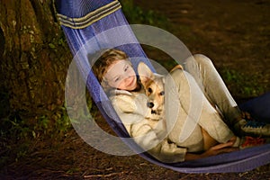 Cute little girl child sleeping in hammock and holding a corgi dog together in camping trip