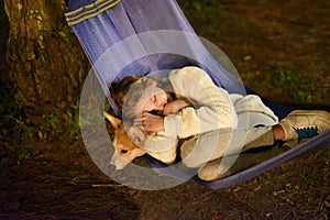 Cute little girl child sleeping in hammock and holding a corgi dog together in camping trip