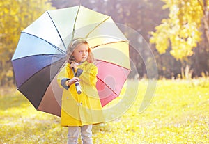 Cute little girl child in yellow jacket with colorful umbrella