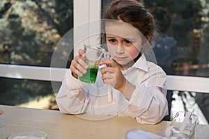 Cute little girl conducts a chemical reactivity with citric acid soda, in the school chemistry lab. Volcanic eruption.