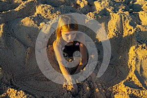 Cute little girl covered with sand. Happy childhood. Relax and play on the beach. Funny kids` activities. Summer concept. Bali,