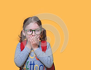 Cute little girl covering mouth with hands. Showing intense expression of fear and terror. Surprised or scared kid