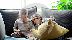 Cute little girl and cute boy playing a competitive video game on a smartphone, fighting over the game
