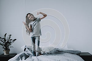 Cute Little Girl Dancing on Bed with Smartphone