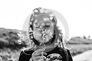Cute little girl with dandelion flower in countryside during a spring sunny day - Female kid having fun and blowing the seeds of