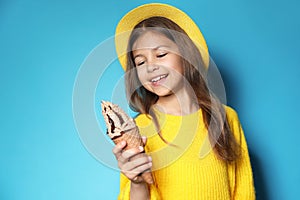 Cute little girl with delicious ice cream against color background