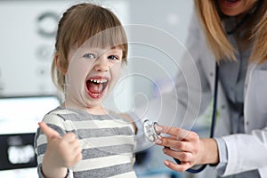 Cute little girl at doctor office showing respect gratitude and approve for quality service with thumb up