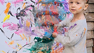 Cute little girl doing fingerpainting with various colors