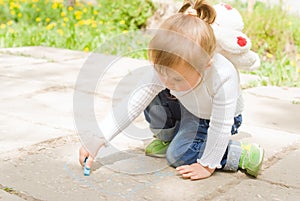 Cute little girl drawing with blue chalk