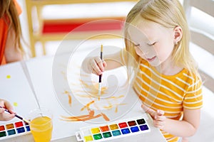 Cute little girl drawing with colorful paints at a daycare. Creative kid painting at school.