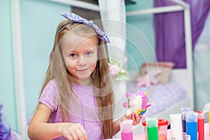 Cute Little girl draws paints at her table in the