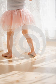 Cute little girl dreams of becoming a ballerina. Child in a pink tutu dancing in a kids room