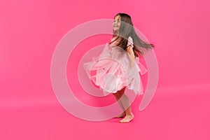 Cute little girl dreams of becoming a ballerina. Little Dancing Girl. Studio Shoot Over Pink Background