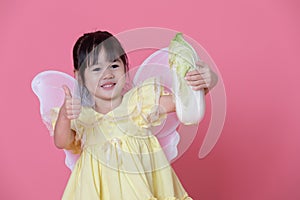 Cute little girl dress up as a angel with white wings holding cabbage and thumb up.Healthy eating and lifestyle concept. Green