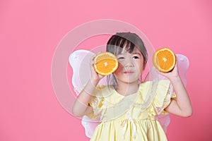 Cute little girl dress up as a angel with white wings holding a half of orange