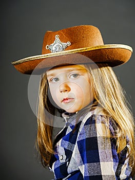 Cute little girl dressed in cowboy shirt and sheriff hat