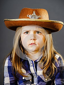 Cute little girl dressed in cowboy shirt and sheriff hat