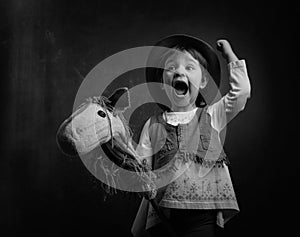 Cute little girl dressed like a cowboy playing with a homemade h