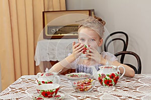 Cute little girl drinking tea at the old table.