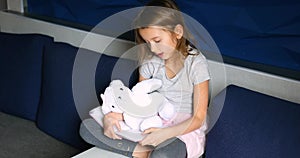 Cute little girl eading a book with stuffed teddy bunny toy