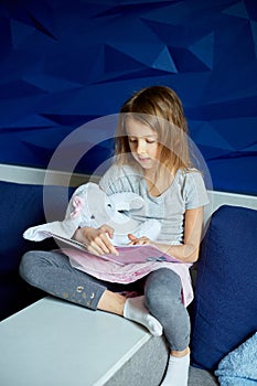 Cute little girl eading a book with stuffed teddy bunny toy photo
