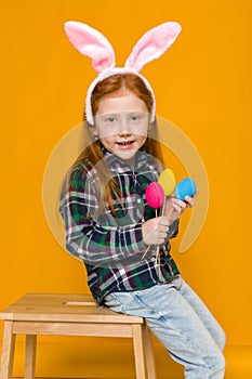 Cute little girl with Easter bunny ears holding colorful eggs