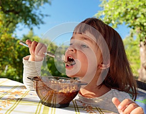 Cute little girl eat flakes with milk .