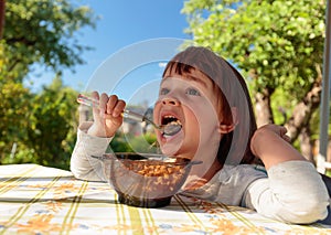 Cute little girl eat flakes with milk .