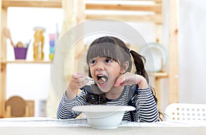 Cute little girl eating cereal with the milk
