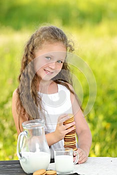 Cute little girl eating chocolate chip cookie on green background