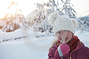 cute little girl while eating icicle on beautiful winter day