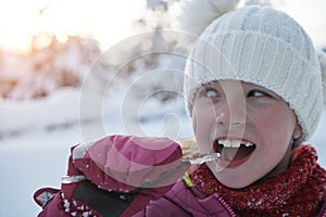 cute little girl while eating icicle on beautiful winter day