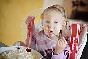 Cute little girl eating porridge photo