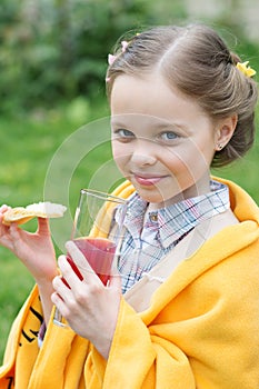 Cute little girl eating snack and drinking juice