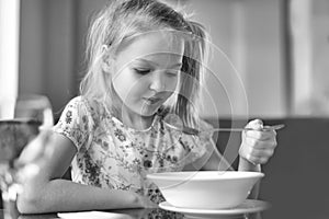 Cute little girl eating a soup in the restaurant