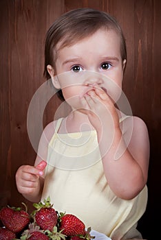 Cute little girl eating strawberries