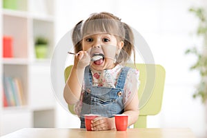 Cute little girl eating yogurt.