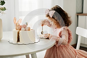 Cute little girl eats a birthday cake with a spoon on her birthday