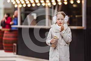A cute little girl eats a traditional Hungarian sweet pastry called Kurtoskalacs in Budapest on the street market at