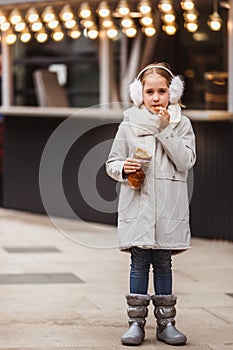 A cute little girl eats a traditional Hungarian sweet pastry called Kurtoskalacs in Budapest on the street market at