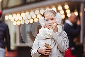 A cute little girl eats a traditional Hungarian sweet pastry called Kurtoskalacs in Budapest on the street market at