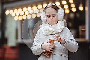 A cute little girl eats a traditional Hungarian sweet pastry called Kurtoskalacs in Budapest on the street market at