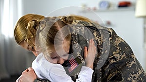 Cute little girl embracing soldier mother in uniform, armed forces duty parting