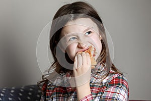 A cute little girl emotionally eating a hamburger, sandwich, cheeseburger or burger and smiling at home