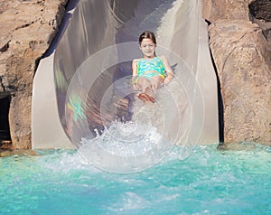 Cute little girl enjoying a wet ride down a water slide