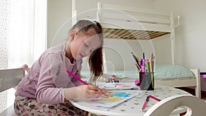 Cute little girl enjoys painting. Girl drawing and coloring picture with color pencil in her room at home