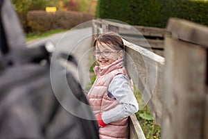 Cute little girl with eyeglasses and backpack on a country road