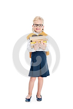 cute little girl in eyeglasses holding pile of books and smiling at camera